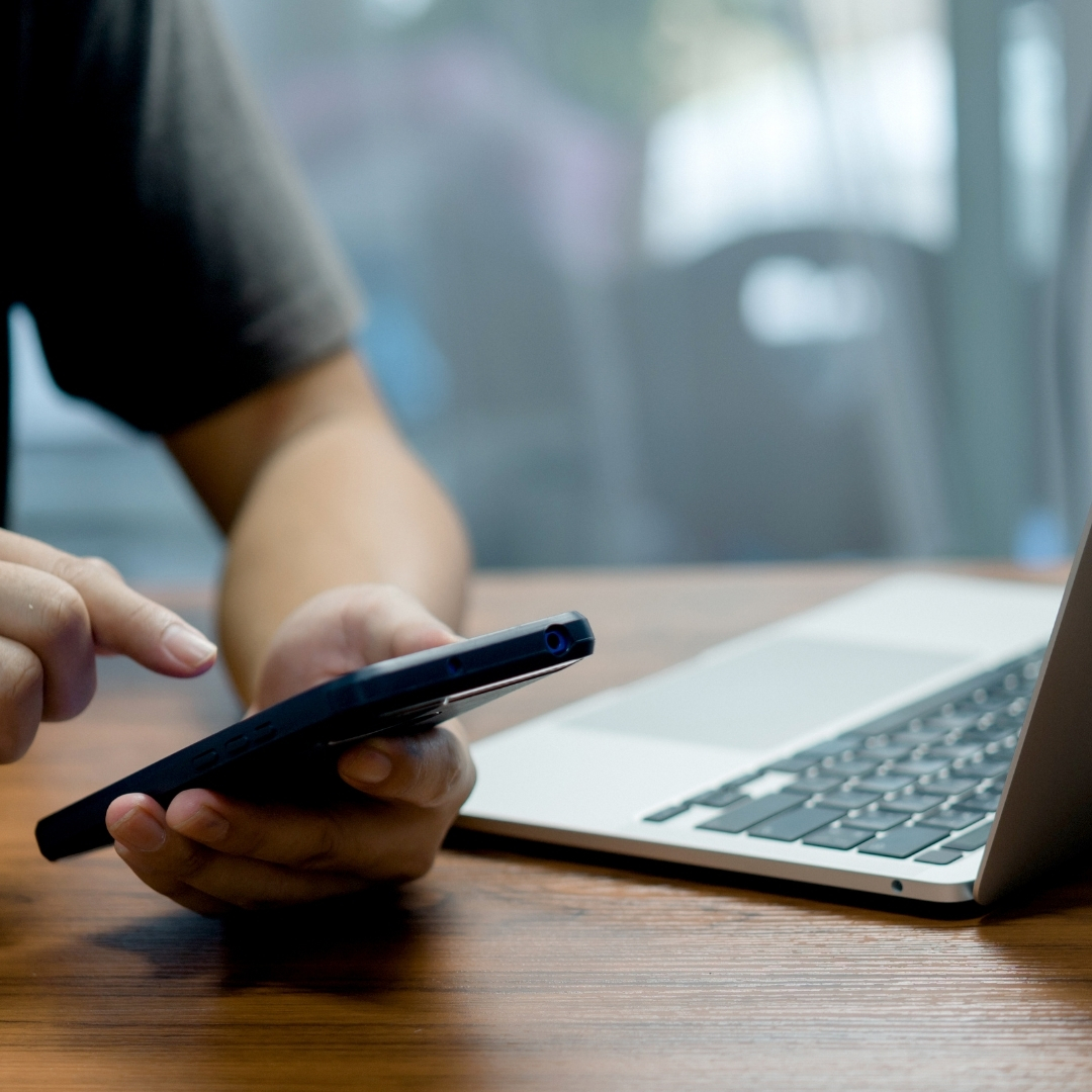 A device configuration in progress on a mobile phone with laptop in background